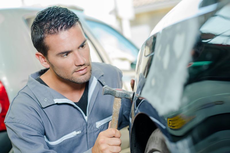 Panel beater working on a car door