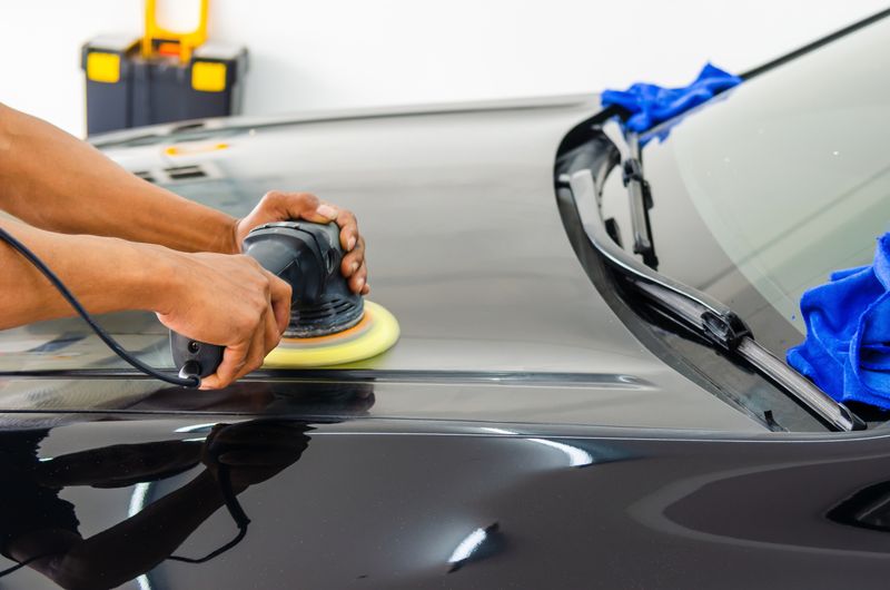 Machine polishing a dark car bonnet